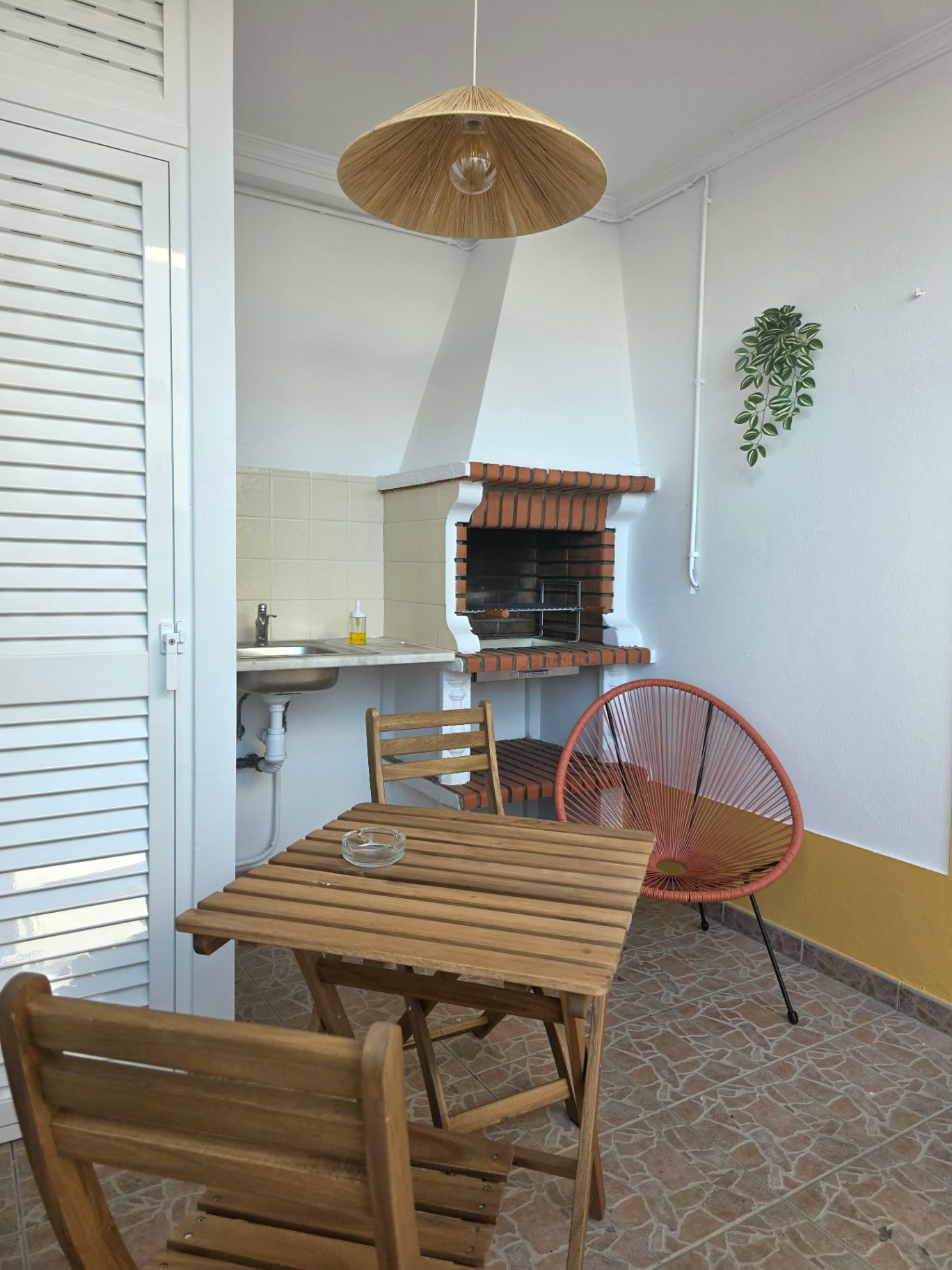 Zona de churrasqueira coberta da Breeze House Almograve com mesa de madeira
